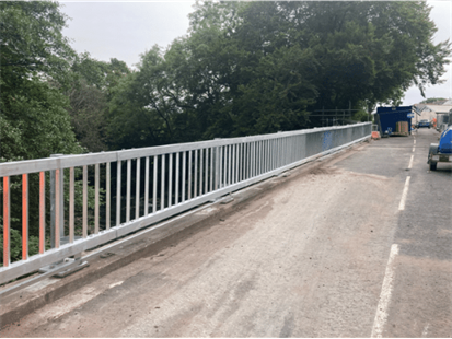 Bridge with silver railings and trees in background